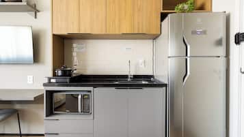 Cocina moderna con horno empotrado, microondas y refrigerador de acero inoxidable.