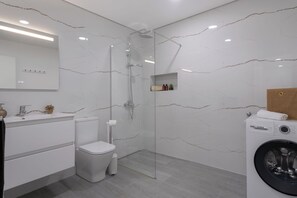 A modern bathroom with a glass shower enclosure, a Bosch washing machine, and a toilet. - Exclusive Oceanview 2-bedroom Apartment|Sol & Mar (Câmara De Lobos)