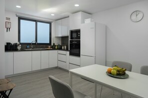 Una cocina moderna con armarios blancos, un horno Bosch y un comedor con una mesa lista para dos.
