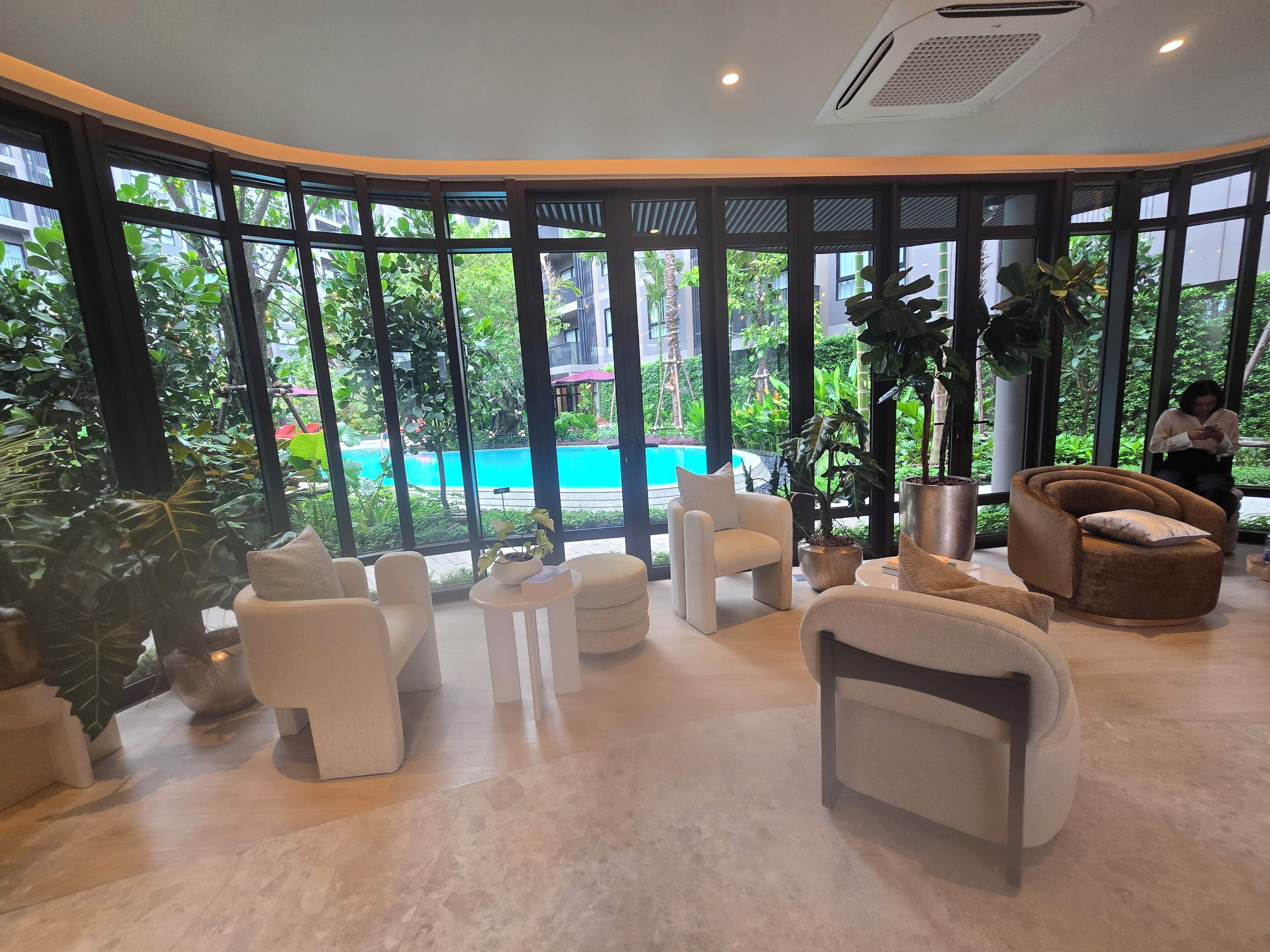 Ein stilvoller Lounge-Bereich mit Sitzgelegenheiten und großen Fenstern mit Blick auf einen Pool.