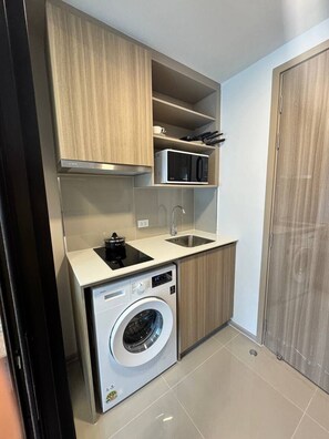 Een compacte keuken met een ingebouwde wasmachine, een magnetron en een spoelbak.