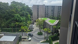 Zona residencial con edificios modernos, estacionamiento y un espacio verde con árboles.