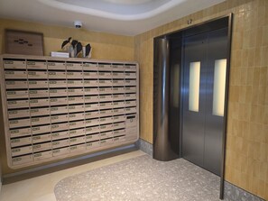 Een hotel lobby met een rij lockers, een receptiebalie en een lift.
