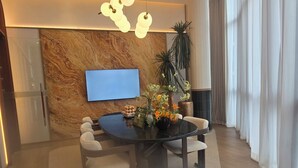 Un comedor moderno con pared de mármol, televisor de pantalla plana y una mesa con sillas.