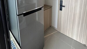 Una cocina compacta con un refrigerador de acero inoxidable, un gabinete de madera y una puerta con picaporte.