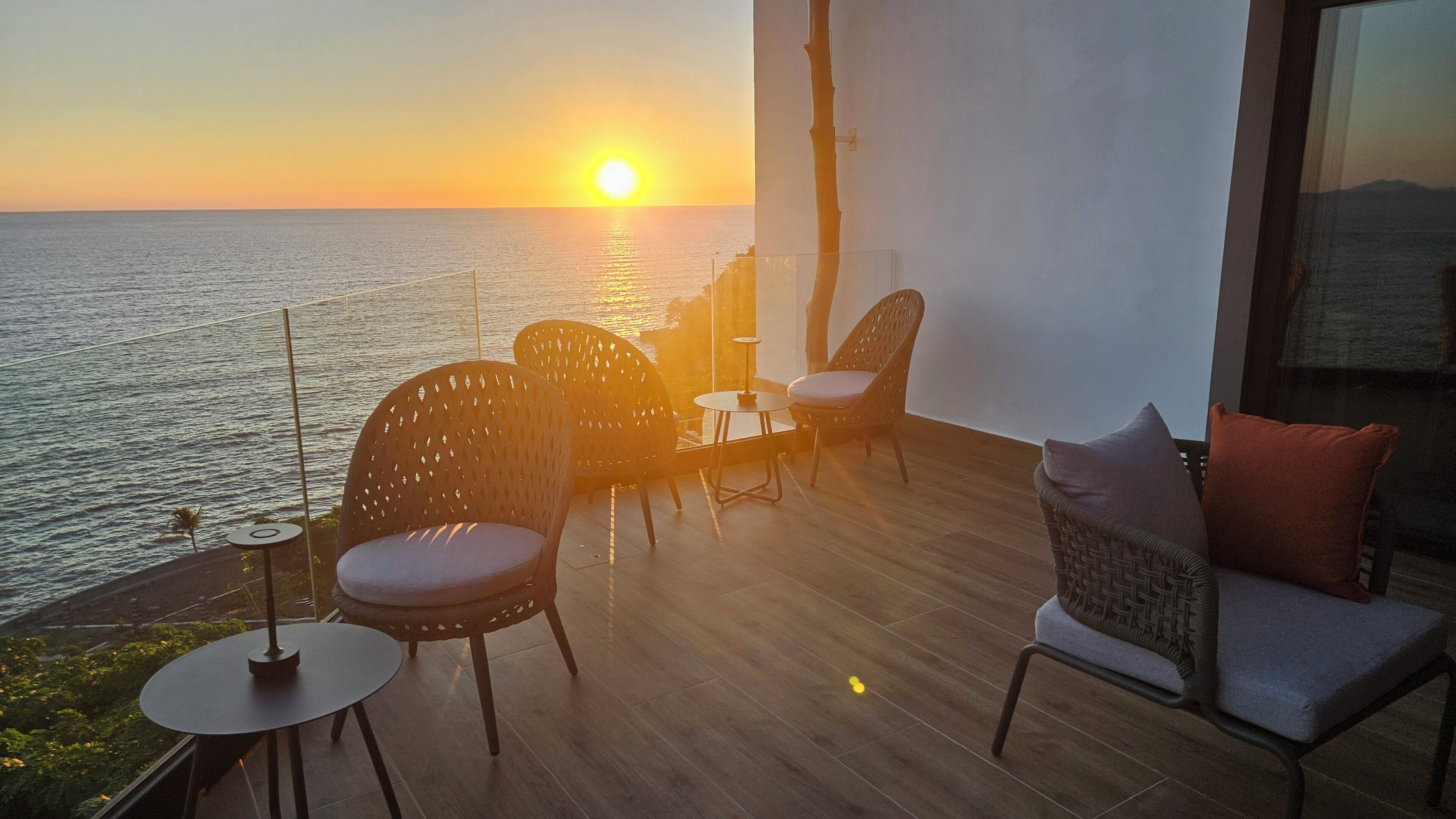 Un balcon avec vue sur la mer, idéal pour admirer le coucher de soleil, et aménagé avec des chaises et une table.