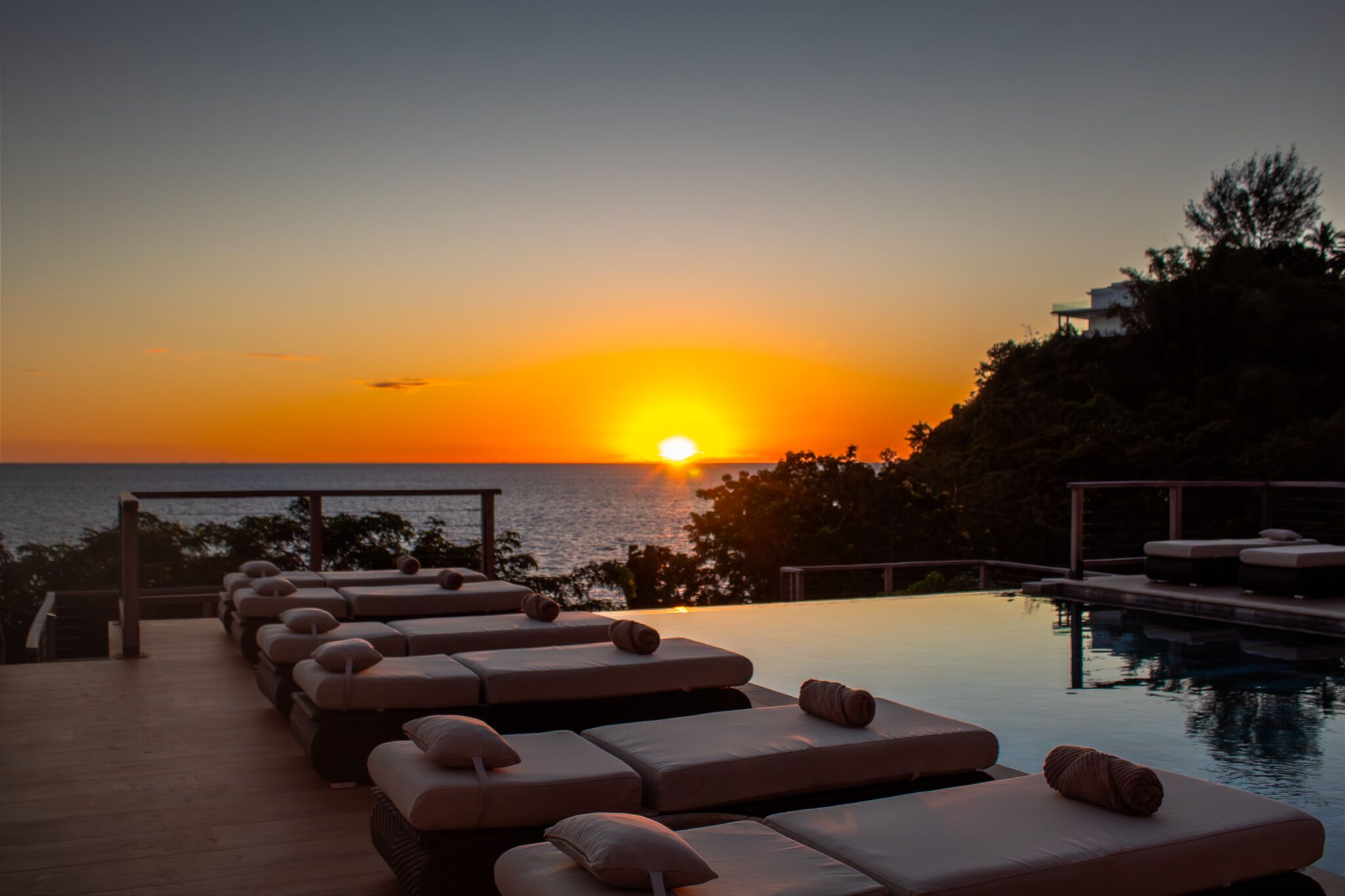 A poolside area with lounge chairs and a sunset view.