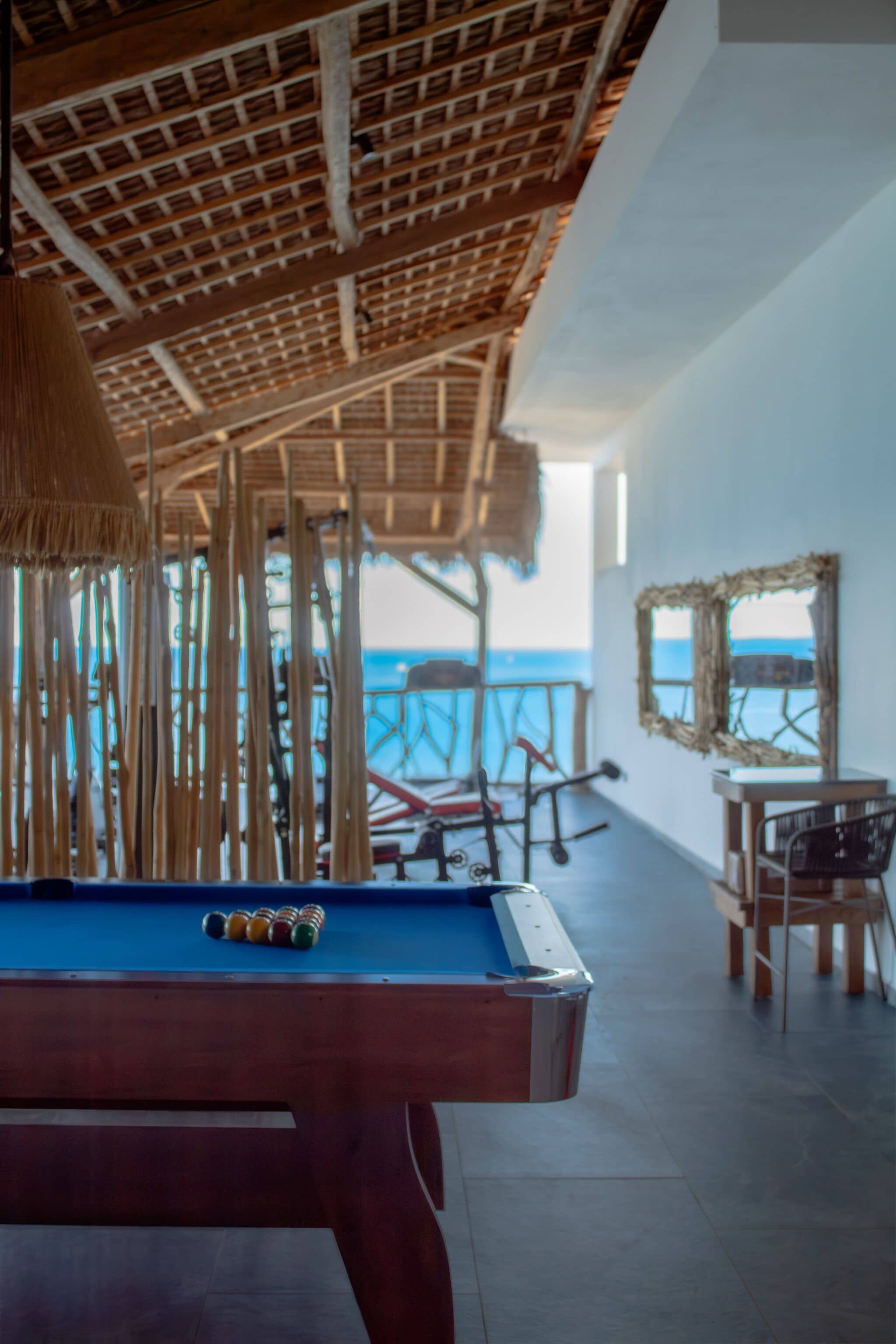 A pool table with a view of the sea and a beach in the background.