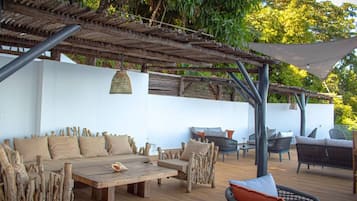 Un espacio exterior con mobiliario de madera y una estructura de pérgola.