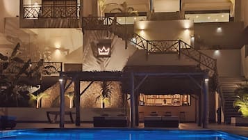 A multi-level building with a pool area, outdoor seating, and a bar.