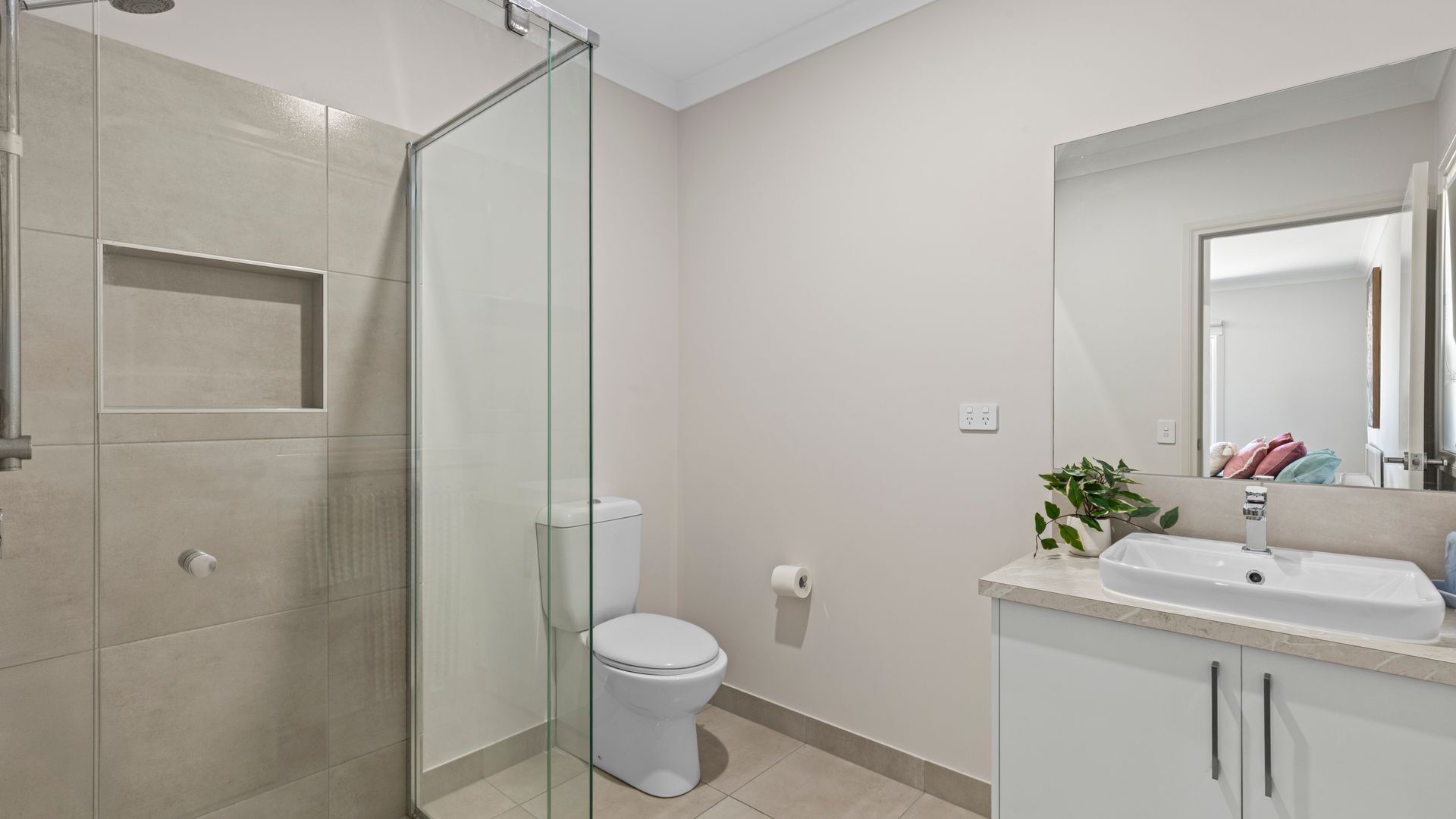 Une salle de bain moderne avec une douche à parois de verre, des toilettes, un lavabo et un miroir.