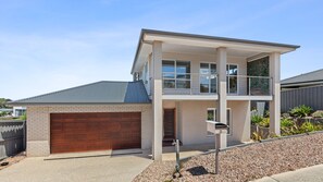 A two-story residential building with a garage, a balcony, and a well-maintained garden. - Pasadena Vista - Your Perfect Holiday Escape (Portarlington)