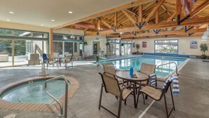 A pool area with a hot tub, lounge chairs, and a covered seating area.
