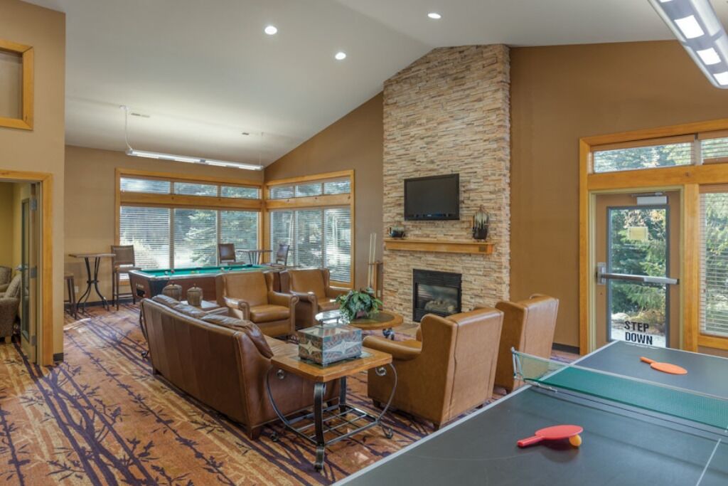 A spacious room with a pool table, comfortable seating, a fireplace, and large windows.