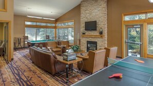 A spacious room with a pool table, comfortable seating, a fireplace, and large windows.