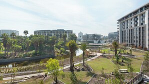 Una zona residenziale moderna con una fontana centrale, circondata da vegetazione e palme.