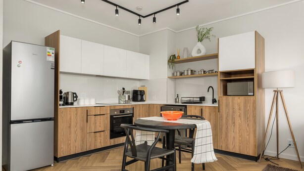 Una cucina moderna con mobili bianchi, un frigorifero nero e un piano di lavoro in legno.