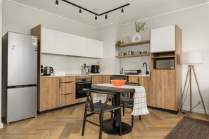Eine moderne Küche mit weißen Schränken, einem schwarzen Kühlschrank und einer Holzarbeitsplatte.