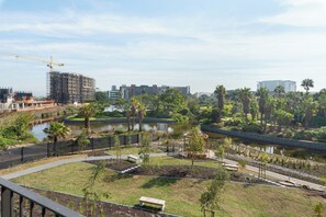 A riverside park with walking paths, benches, and a construction site in the background. - Park Place | Lush Apartment | Balcony and Lake Views (Cape Town)
