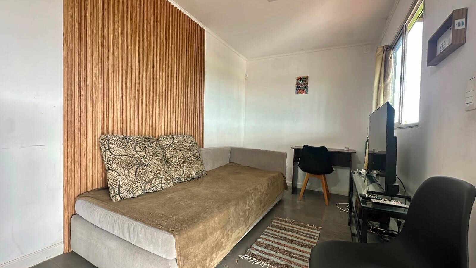 Una habitación pequeña con cama, escritorio y silla.