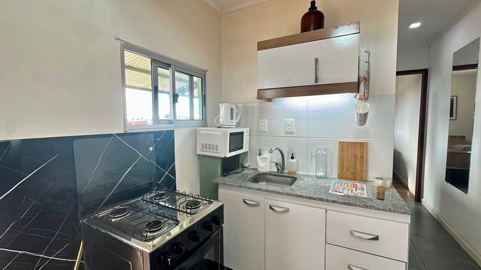 Una cocina moderna con estufa a gas, microondas y pileta.