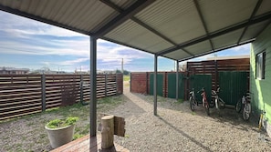 A covered outdoor area with a gravel floor, wooden fence, and bicycles.