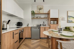 Eine moderne Küche mit Holdekor, einem eingebauten Geschirrspüler und einer Essecke mit Tisch für zwei Personen.