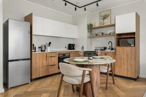Eine moderne Küche mit Holzausbau, einem eingebauten Backofen und einem Esstisch mit Stühlen.