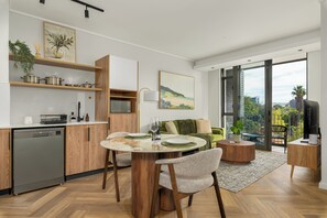 Eine moderne Küche mit Holzschränken, einem Geschirrspüler und einem Essbereich mit rundem Tisch und Stühlen.