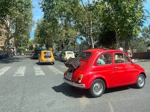 A red vintage car parked on a street lined with trees and buildings. - Monti Mood Design Apt - via Urbana - Rome (Rome)