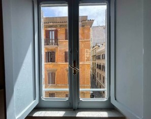 Ein Fenster mit Blick auf ein Mehrfamilienhaus mit Balkonen.