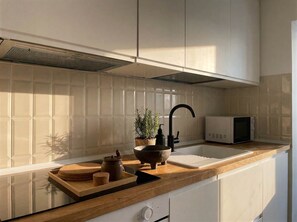 A kitchen with a sink, a microwave, a potted plant, and a wooden cutting board. - Monti Mood Design Apt - via Urbana - Rome (Rome)