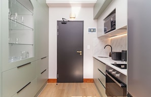 A compact kitchen with a dark door, a glass cabinet with wine glasses, a microwave, and a toaster. - Charlie and the Chairman | Vibrant City Escape (Cape Town)