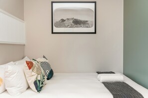 A bedroom with a bed, pillows, a blanket, and a framed picture on the wall. - Charlie and the Chairman | Vibrant City Escape (Cape Town)