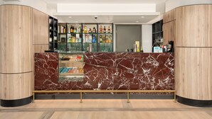 Eine moderne Bar mit Marmorplatten, Regalen voller Spirituosenflaschen und einer Glasvitrine.