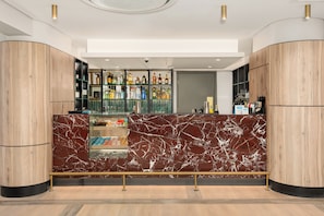 A modern bar area with marble countertops, shelves of liquor bottles, and a glass display case. - Charlie and the Chairman | Vibrant City Escape (Cape Town)