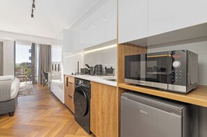 A modern kitchen with a Bosch microwave, a washing machine, and a refrigerator. - Stylish Apartment | Balcony and Pool (Cape Town)