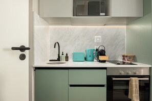 Een moderne keuken met een ingebouwde magnetron, een spoelbak, een waterkoker en een fornuis.