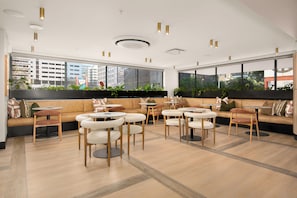 Ein stilvoller Lounge-Bereich mit Sofas, runden Tischen und Topfpflanzen.