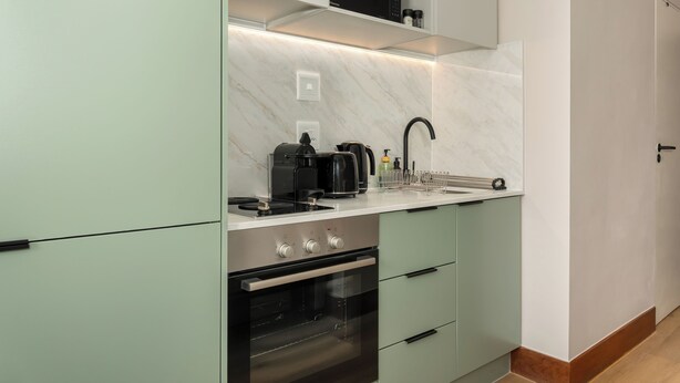 Eine moderne Küche mit integriertem Backofen, einer Kaffeemaschine und einem Wasserkocher auf der Arbeitsfläche.