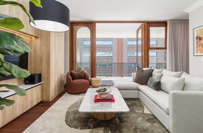 Ein modernes Wohnzimmer mit einer Couch, einem Couchtisch und einem großen Fenster.
