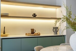 Une cuisine avec une étagère en bois, un saladier, une carafe et un vase.