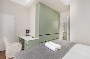 Une chambre à coucher avec un lit, un bureau, une chaise et une armoire.