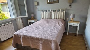 A bedroom with a bed, two bedside tables, a radiator, and a window. - La Zénitude***, a house located 150 m from the Bassin—relaxation guaranteed (Lège-Cap-Ferret)
