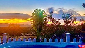 Una piscina con vistas a la puesta de sol y montañas al fondo.