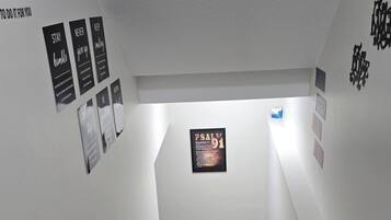 A staircase with wooden steps and metal handrails, leading to a landing with a framed inspirational quote.
