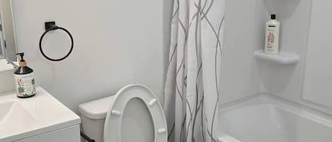 A bathroom with a toilet, a shower, and a sink.
