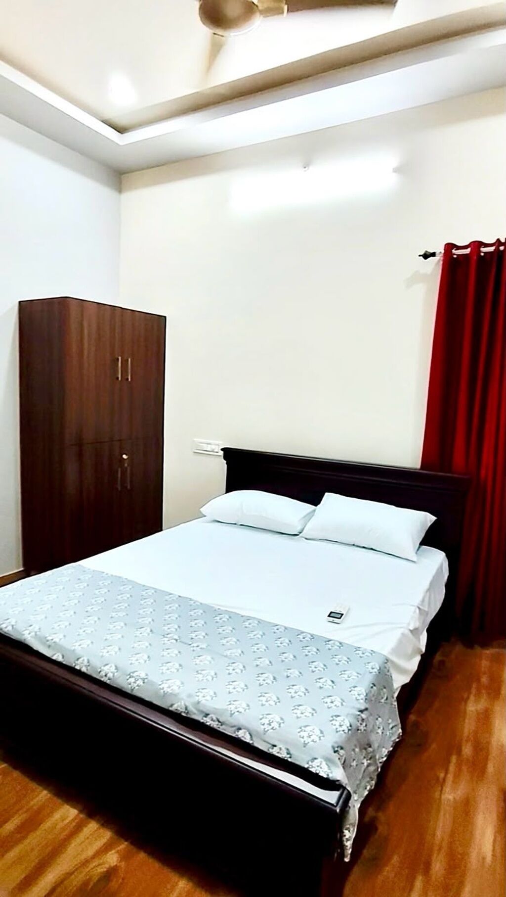 A bedroom with a bed, a wardrobe, and a red curtain.