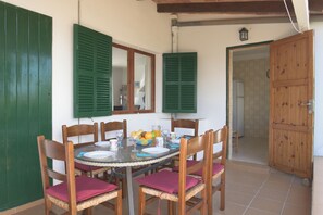 A dining area with a round table, chairs, and a bowl of fruit. - Holiday home for 6 people with private pool, barbecue  Wi-Fi, air conditioning (Santanyí)