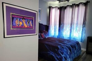 A bedroom with a bed, curtains, and a framed picture on the wall. - Delightfully Villainous (Four Corners)